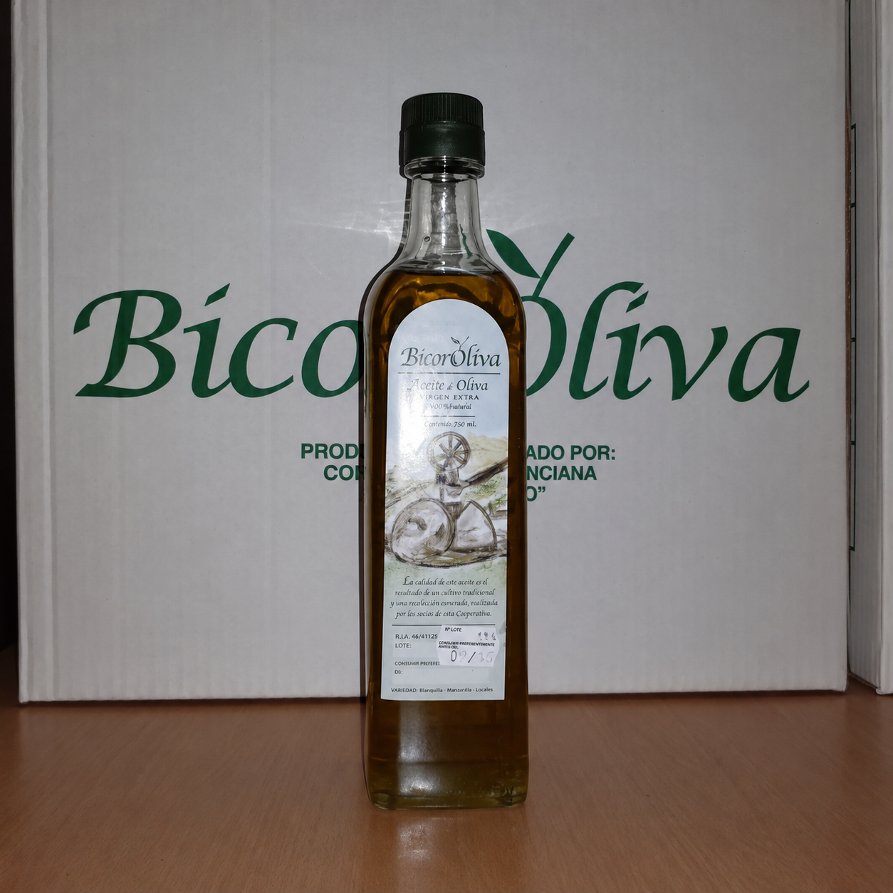 Botella de aceite BicorOliva ante las cajas de la cooperativa
