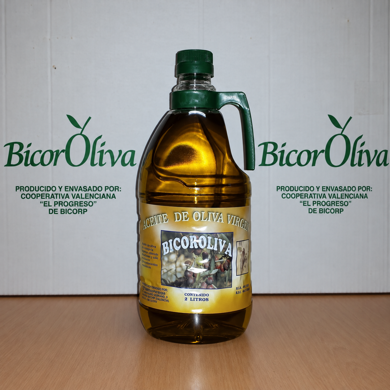 Garrafa de 2 litros de aceite BicorOliva ante las cajas de la cooperativa